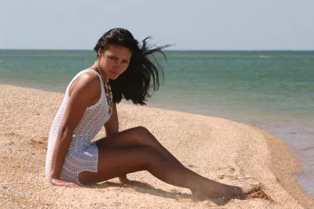 Черноволосая  в белом платьице на пляже